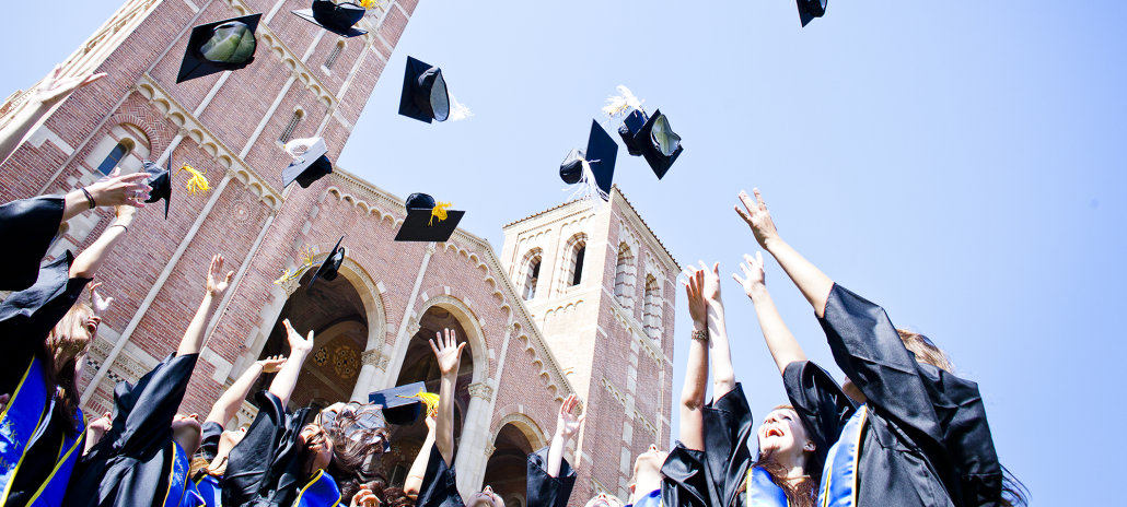 Picture of graduates in front of Royce Hall throwing caps in the air.